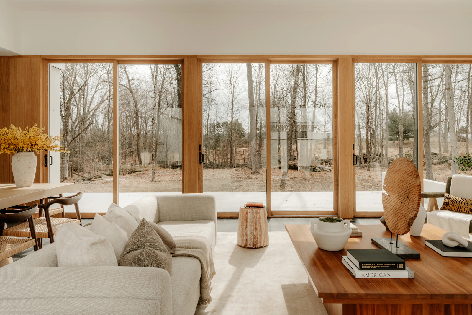Inviting living room with cream seating, natural wood furniture and large windows looking onto trees